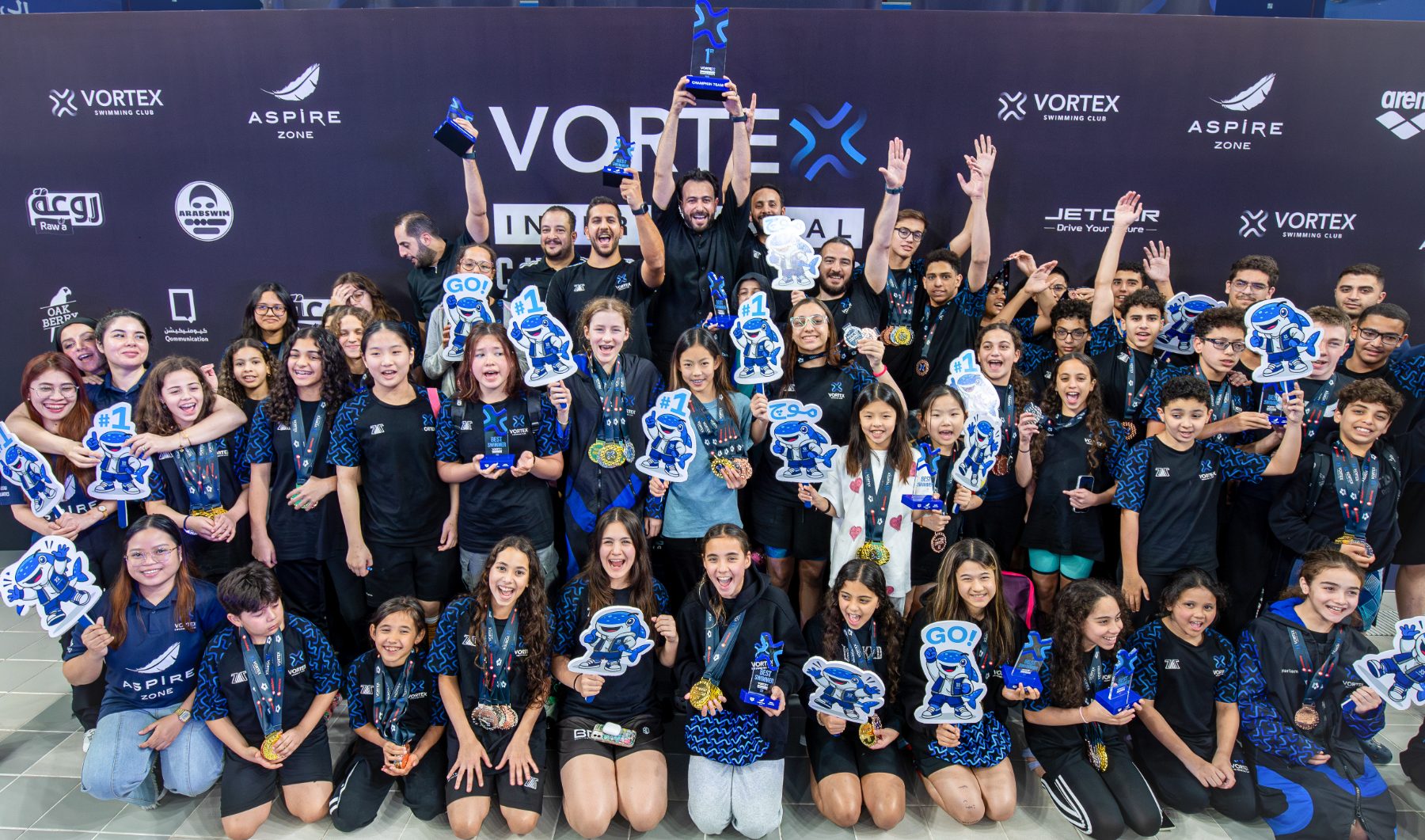 Vortex Swimming Club celebrating with medals and the champion team trophy