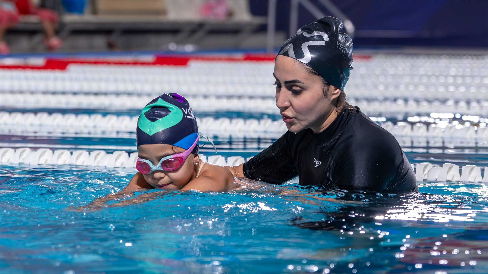 A coach teaching a young child to swim at Vortex Academy